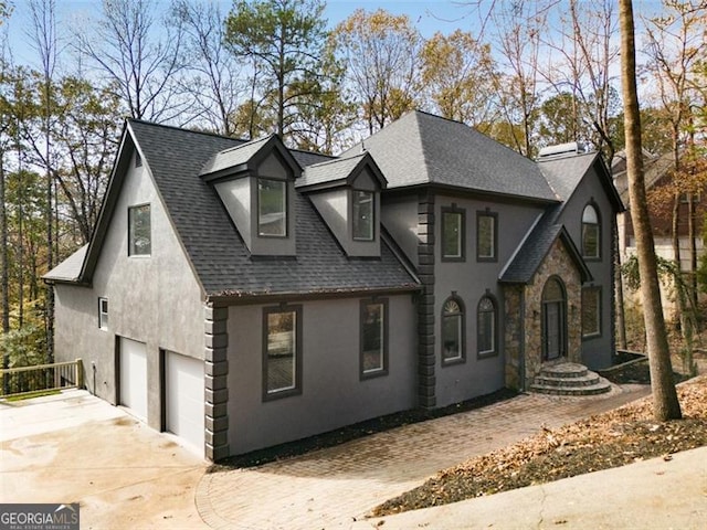 view of front of home with a garage, concrete driveway, roof with shingles, and stucco siding