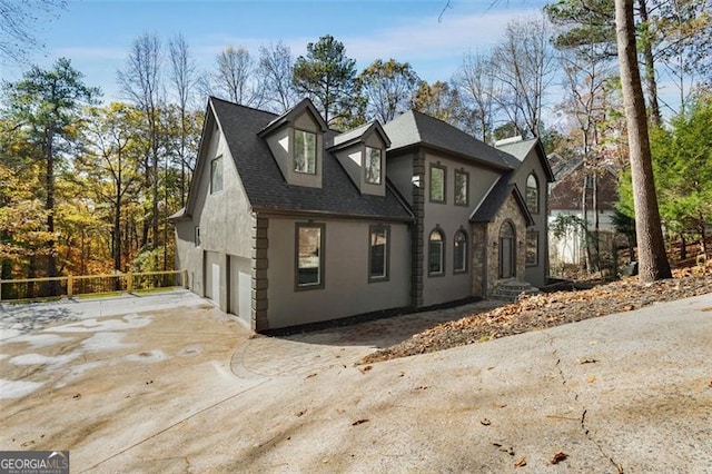 view of front facade featuring driveway, a shingled roof, and stucco siding