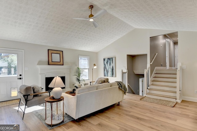 living room with light wood-style floors, a healthy amount of sunlight, and stairs