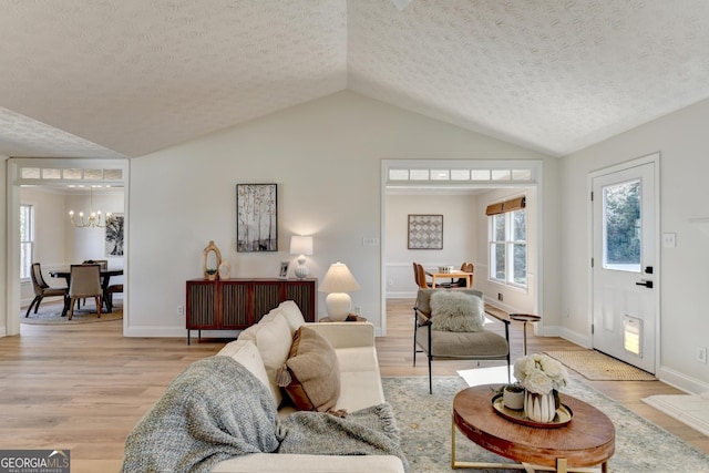 living room featuring vaulted ceiling, light wood-type flooring, and an inviting chandelier