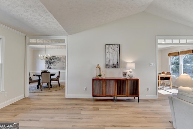 living area featuring lofted ceiling, a notable chandelier, light wood-style flooring, and a textured ceiling