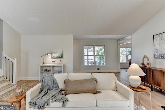 living area featuring stairs, wood finished floors, and baseboards