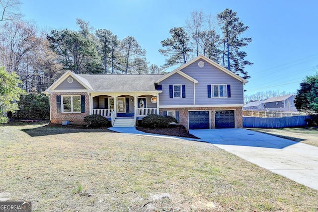 tri-level home with brick siding, a porch, a garage, driveway, and a front lawn