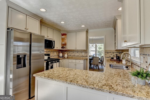 kitchen with a peninsula, tasteful backsplash, appliances with stainless steel finishes, and a sink