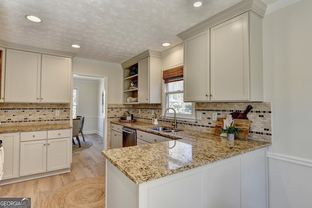 kitchen featuring light stone counters, a sink, backsplash, open shelves, and light wood finished floors