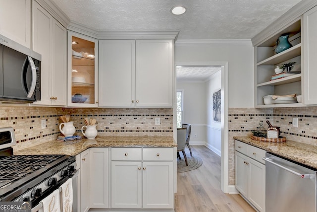 kitchen with light wood finished floors, open shelves, appliances with stainless steel finishes, ornamental molding, and a textured ceiling