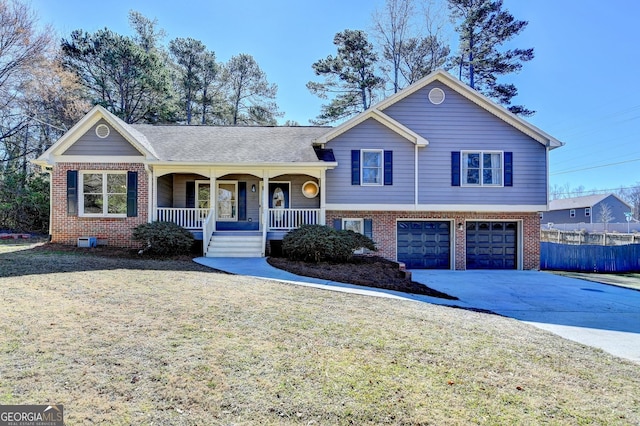 tri-level home featuring a porch, a garage, brick siding, driveway, and a front yard