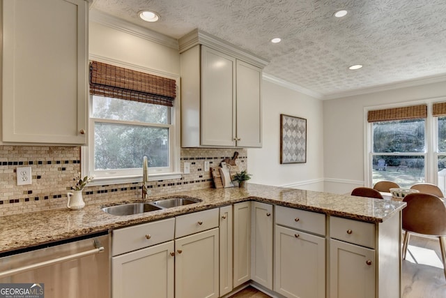 kitchen featuring light stone counters, a peninsula, a sink, ornamental molding, and stainless steel dishwasher