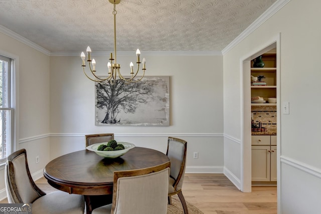 dining area with light wood-type flooring, crown molding, a chandelier, and a textured ceiling