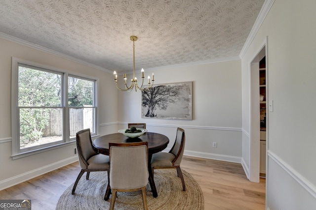 dining area featuring light wood finished floors, baseboards, ornamental molding, and an inviting chandelier