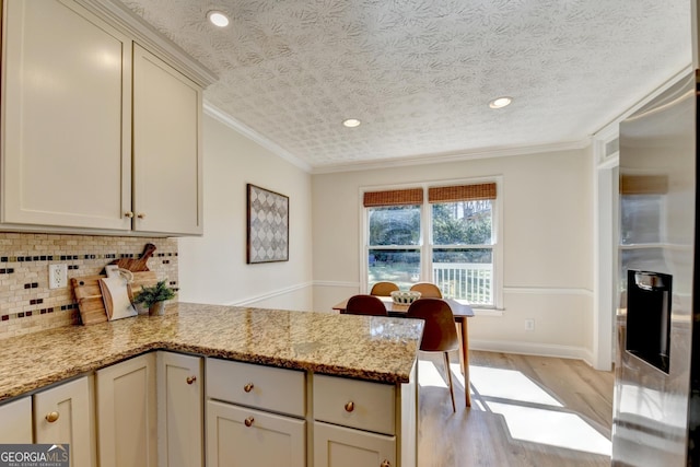 kitchen with decorative backsplash, light wood-style floors, ornamental molding, a peninsula, and stainless steel fridge with ice dispenser