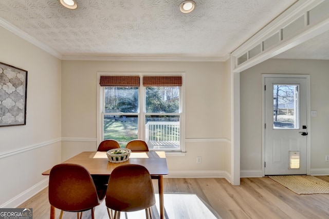 dining space featuring light wood-type flooring, a healthy amount of sunlight, a textured ceiling, and baseboards