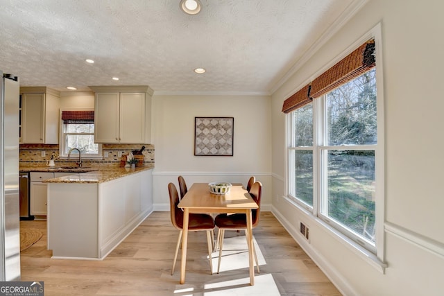 dining room with light wood-type flooring, visible vents, ornamental molding, and a textured ceiling