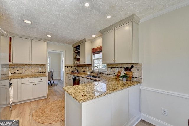 kitchen with light stone counters, open shelves, light wood-style floors, a sink, and dishwasher