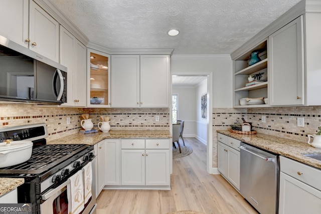 kitchen with a textured ceiling, light wood-style flooring, stainless steel appliances, open shelves, and crown molding