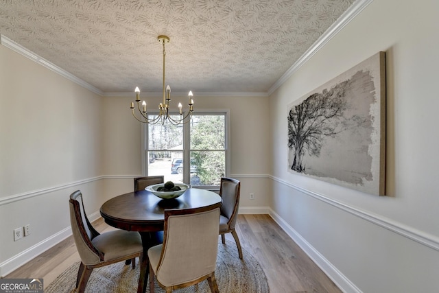 dining room featuring an inviting chandelier, ornamental molding, a textured ceiling, wood finished floors, and baseboards