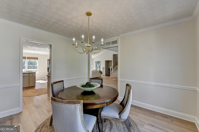 dining room with light wood-style floors, crown molding, a textured ceiling, and a notable chandelier