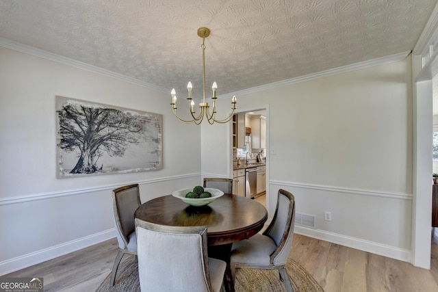 dining area with ornamental molding, light wood finished floors, visible vents, and a notable chandelier