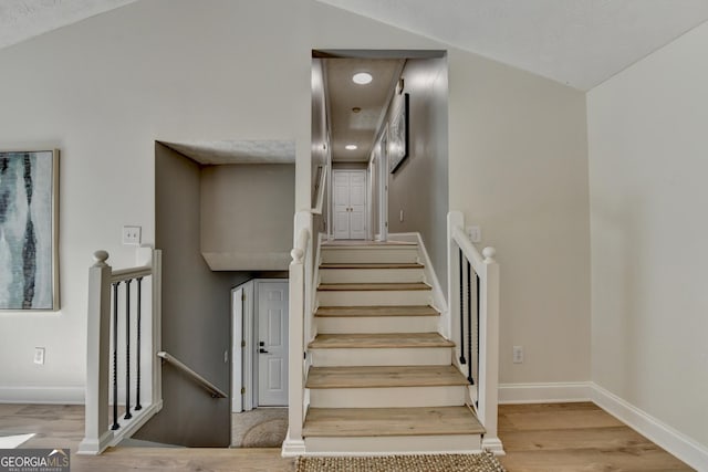 stairs with vaulted ceiling, wood finished floors, and baseboards