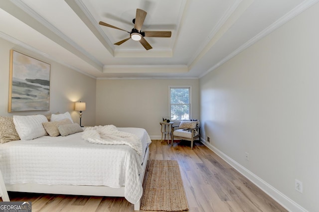 bedroom with ceiling fan, baseboards, light wood-style floors, a raised ceiling, and crown molding