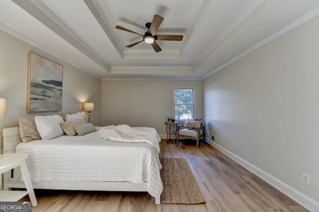 bedroom with wood finished floors, a ceiling fan, baseboards, ornamental molding, and a raised ceiling