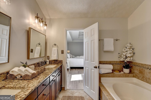 ensuite bathroom with a bath, a textured ceiling, a sink, and ensuite bathroom