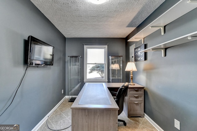 office area with light tile patterned floors, baseboards, and a textured ceiling