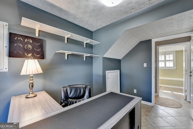 office space featuring baseboards, vaulted ceiling, and a textured ceiling