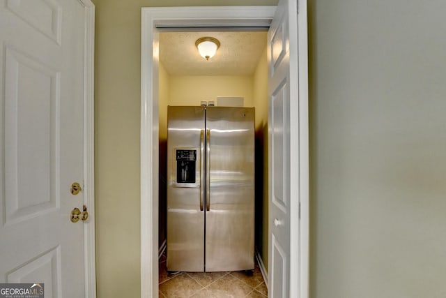 kitchen featuring a textured ceiling, light tile patterned floors, and stainless steel fridge