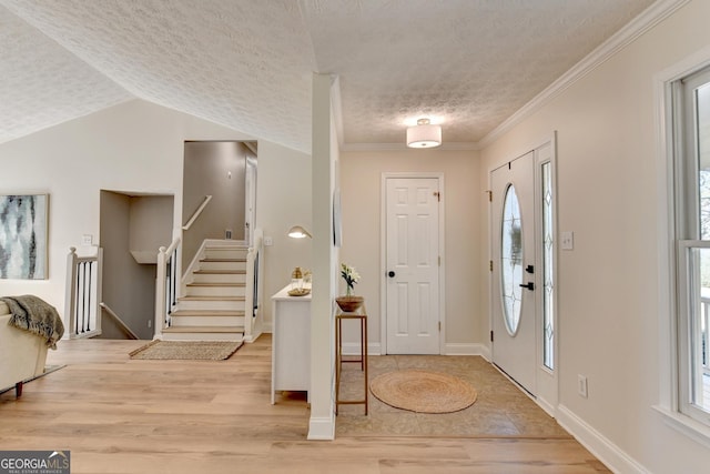 foyer entrance with light wood-style flooring, crown molding, stairway, and a textured ceiling