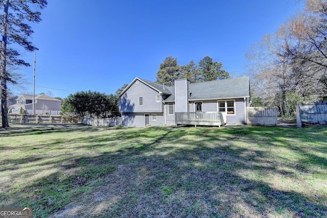 rear view of house with fence and a lawn