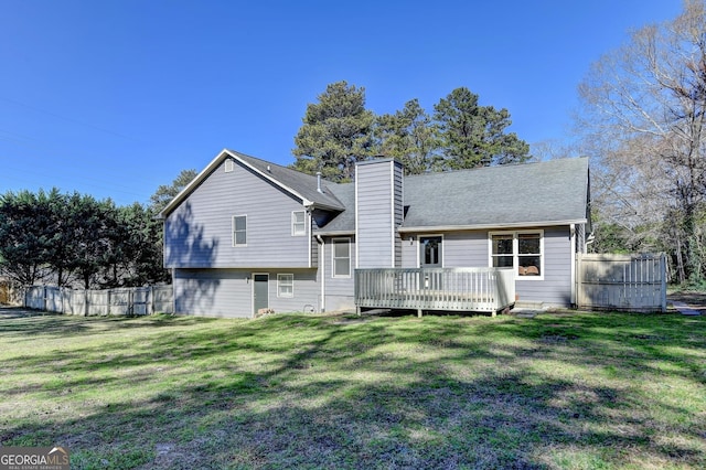 rear view of house featuring fence and a lawn