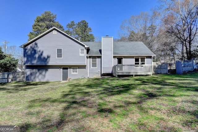 back of house featuring a chimney, fence, a deck, and a yard