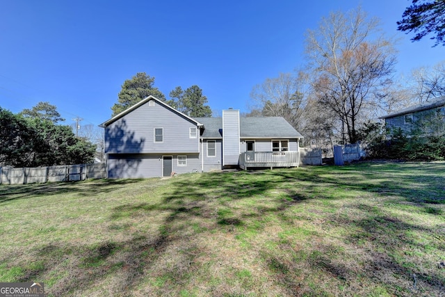 rear view of property featuring a deck, a yard, a chimney, and fence