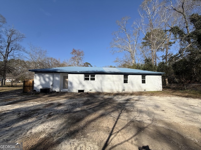 exterior space featuring metal roof, central AC unit, brick siding, fence, and crawl space