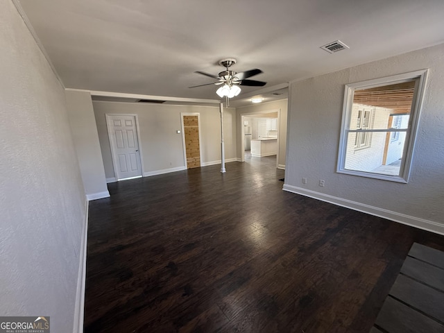 unfurnished living room with visible vents, dark wood finished floors, baseboards, a textured wall, and ceiling fan