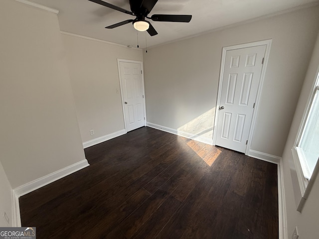 unfurnished bedroom featuring crown molding, ceiling fan, dark wood finished floors, and baseboards