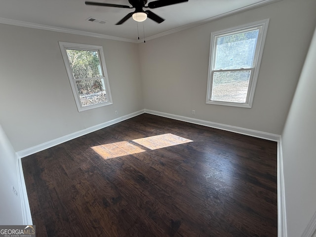 spare room with dark wood-style floors, visible vents, crown molding, and baseboards