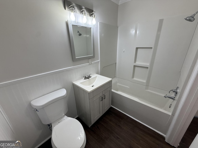 bathroom with toilet, a wainscoted wall, wood finished floors, vanity, and shower / washtub combination