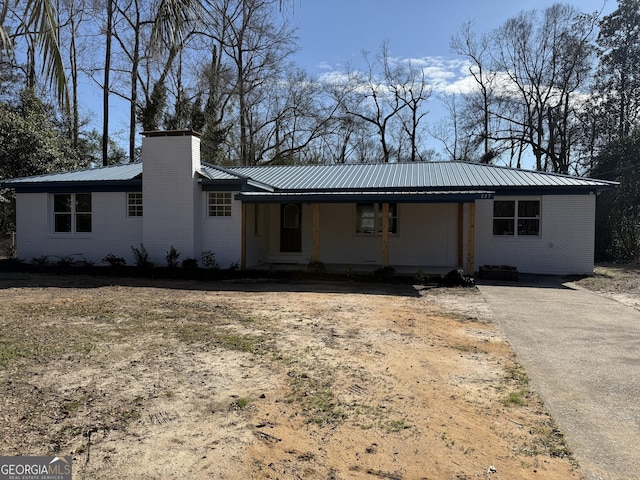 view of front of home with brick siding, metal roof, and a chimney