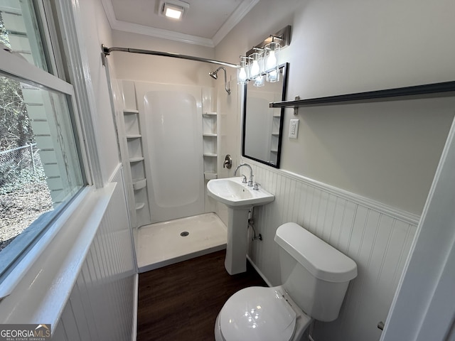 bathroom with a wainscoted wall, crown molding, toilet, a shower stall, and wood finished floors