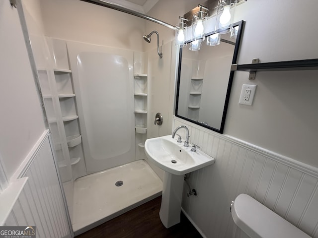 full bath featuring a stall shower, wainscoting, toilet, and wood finished floors