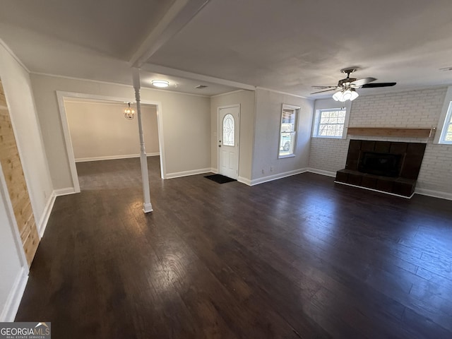 unfurnished living room with brick wall, dark wood-type flooring, a brick fireplace, and a ceiling fan