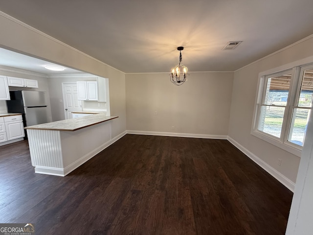 unfurnished dining area with dark wood-style flooring, visible vents, baseboards, ornamental molding, and an inviting chandelier