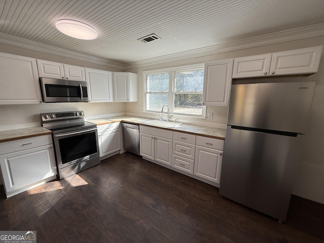 kitchen featuring dark wood-style flooring, stainless steel appliances, light countertops, white cabinetry, and a sink