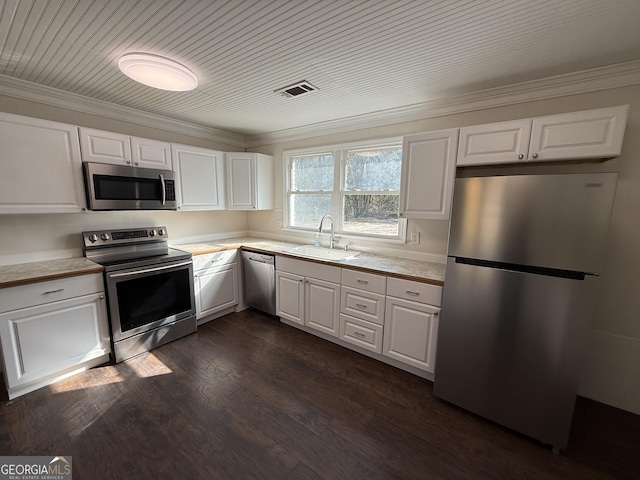 kitchen with light countertops, appliances with stainless steel finishes, a sink, and white cabinets