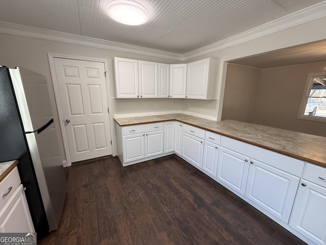 kitchen featuring white cabinets, ornamental molding, dark wood-type flooring, freestanding refrigerator, and light countertops