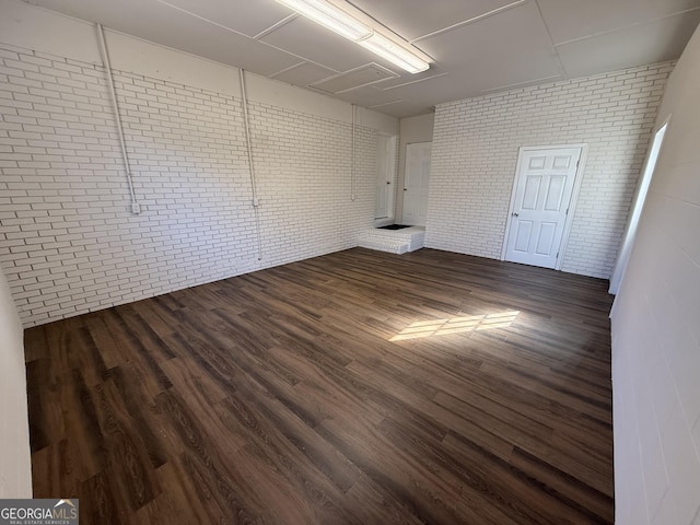 empty room with brick wall and dark wood finished floors