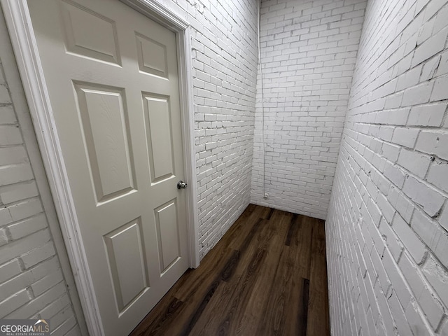 hall featuring brick wall and dark wood-style flooring