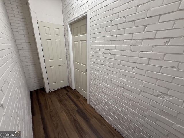 hall featuring dark wood-type flooring and brick wall